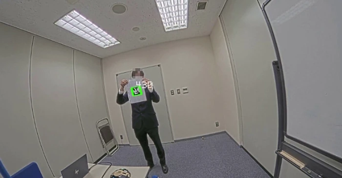 人が掲げたARマーカーを、カメラの映像の上で枠と番号で示している画面